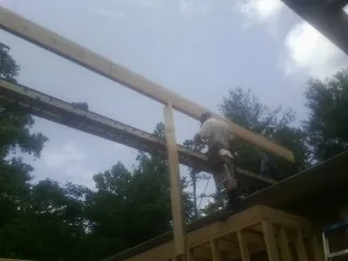 Carpenter setting a ridge beam over a new addition frame — Ice Dam Removal by Roofing Brothers in Waretown