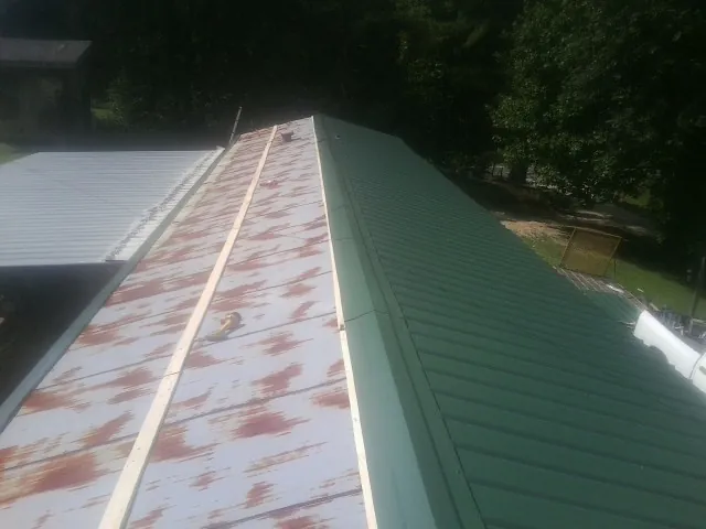 Old rusted panels beside newly installed green metal roofing — Wind Damage Roof Repair by Roofing Brothers in Waretown