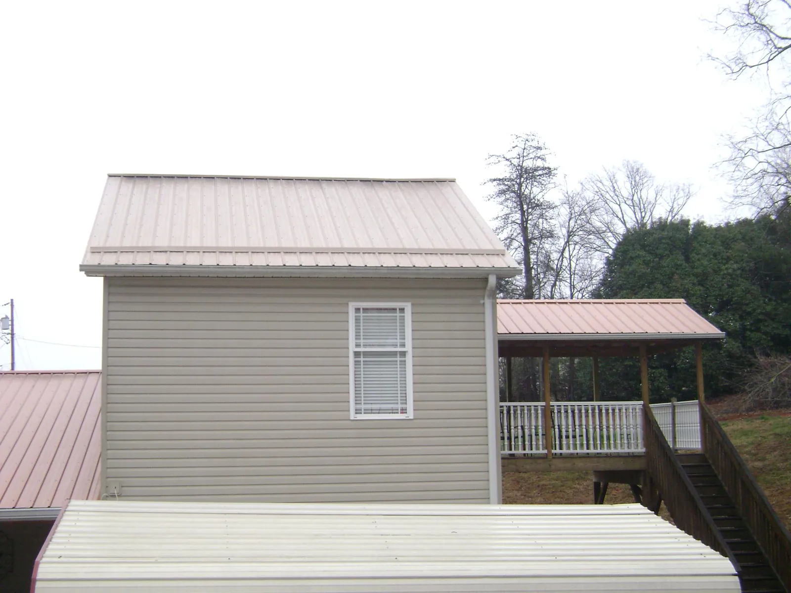 Tan metal roofs on a two story addition and attached porch, from a Roof Replacement job in Waretown