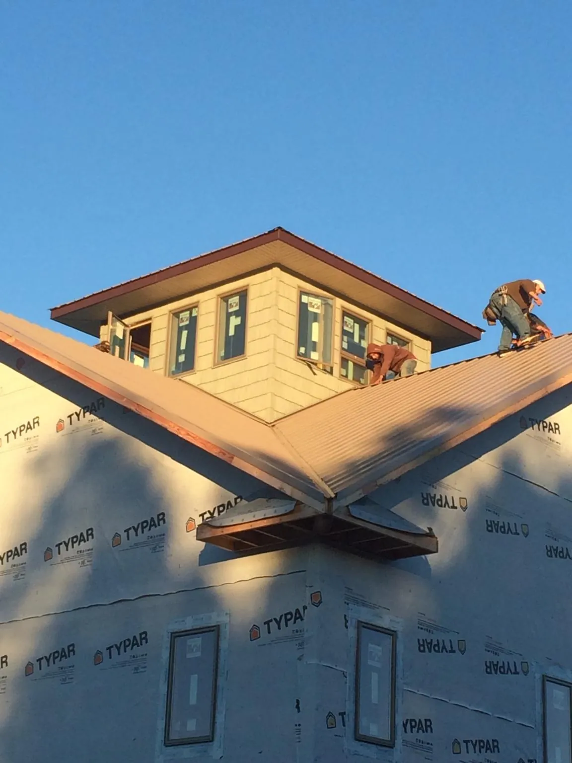 Roofers working around a rooftop cupola on a new metal roof at sunset — Roof Waterproofing in Waretown by Roofing Brothers